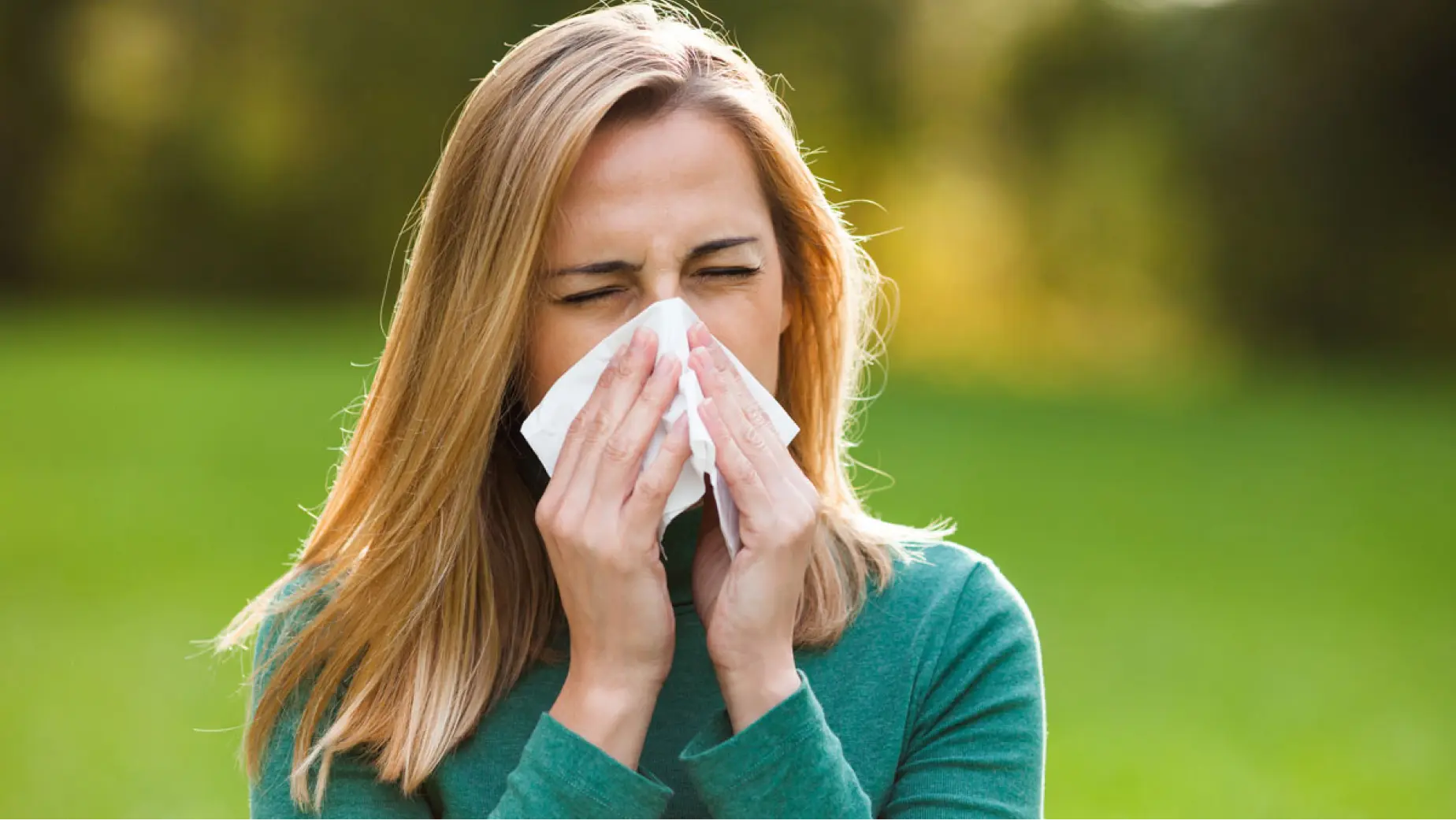 Mujeres sufriendo de alergias y sonándose la nariz al aire libre