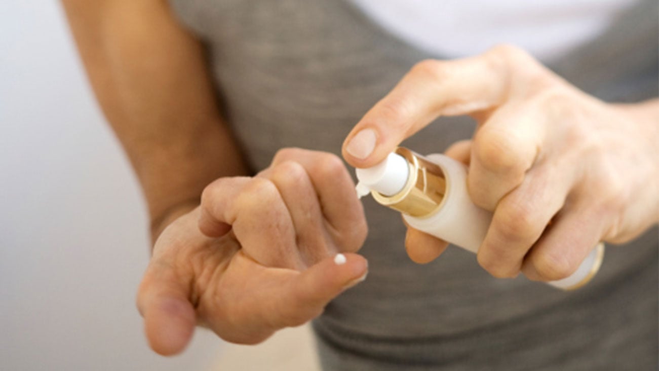 Person dispensing a drop of facial moisturizer on their finger
